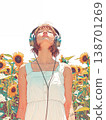 A woman listening to music in a sunflower field 138701269