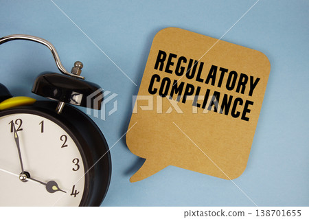 Regulatory Compliance text with alarm clock on blue background Regulatory Compliance text with alarm clock on blue background 138701655