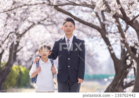 A pair of brothers, one elementary school student and the other middle school student, begin the new school term amidst the full bloom of cherry blossoms. 138702442