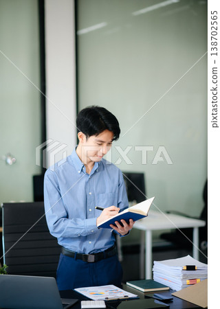 Confident Asian businessman typing laptop computer and digital tablet at office Confident Asian businessman typing laptop computer and digital tablet at office 138702565