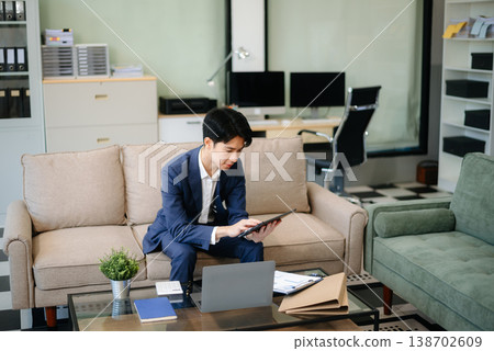 Confident entrepreneur multitasking with a laptop and phone in a modern office. Perfect for business, remote work, finance Confident entrepreneur multitasking with a laptop and phone in a modern office. Perfect for business, remote work, finance 138702609