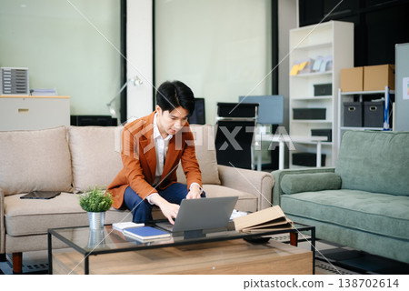 Confident entrepreneur multitasking with a laptop and phone in a modern office. Perfect for business, remote work, finance Confident entrepreneur multitasking with a laptop and phone in a modern office. Perfect for business, remote work, finance 138702614