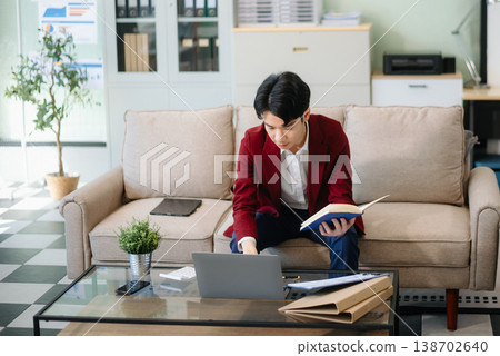 Confident young businessman working on a laptop, analyzing documents in a stylish modern office. Confident young businessman working on a laptop, analyzing documents in a stylish modern office. 138702640