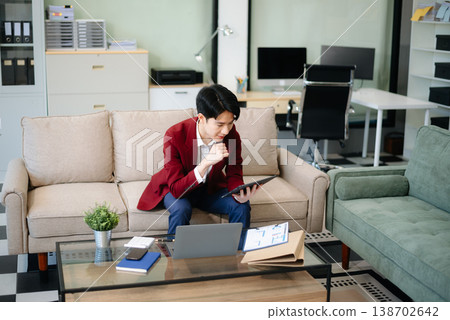 Confident entrepreneur multitasking with a laptop and phone in a modern office. Perfect for business, remote work, finance Confident entrepreneur multitasking with a laptop and phone in a modern office. Perfect for business, remote work, finance 138702642