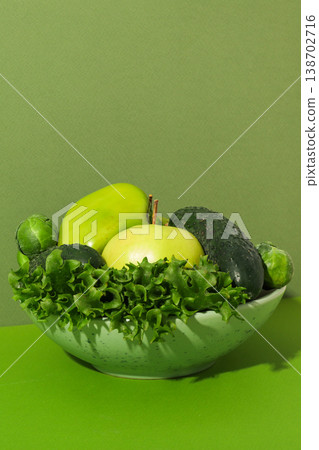 A bowl holds green fruits and vegetables on a plain background 138702716