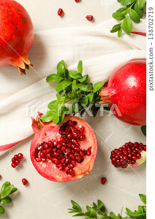 Pomegranates and green leaves arranged on a light surface Pomegranates and green leaves arranged on a light surface 138702719