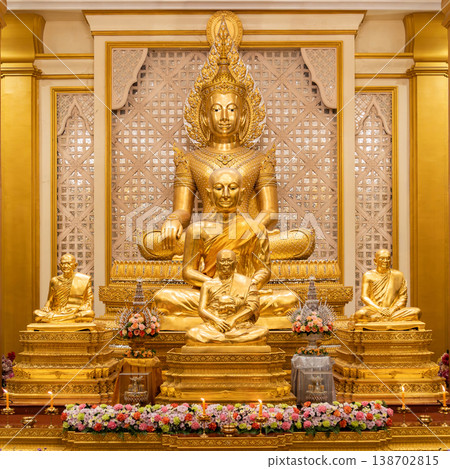 A golden Buddha shrine fills the hall with seated statues and flower rows. Chandeliers and columns frame the symmetrical altar. A golden Buddha shrine fills the hall with seated statues and flower rows. Chandeliers and columns frame the symmetrical altar. 138702815