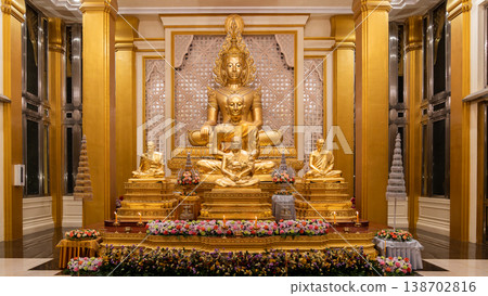 A golden Buddha shrine fills the hall with seated statues and flower rows. Chandeliers and columns frame the symmetrical altar. A golden Buddha shrine fills the hall with seated statues and flower rows. Chandeliers and columns frame the symmetrical altar. 138702816