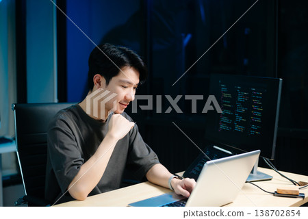 Asian male programmer working with tablet, laptop, and desktop in tech office. Coding, software development 138702854