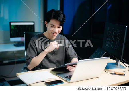 Asian male programmer working with tablet, laptop, and desktop in tech office. Coding, software development Asian male programmer working with tablet, laptop, and desktop in tech office. Coding, software development 138702855