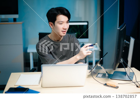 Asian male programmer working with tablet, laptop, and desktop in tech office. Coding, software development Asian male programmer working with tablet, laptop, and desktop in tech office. Coding, software development 138702857