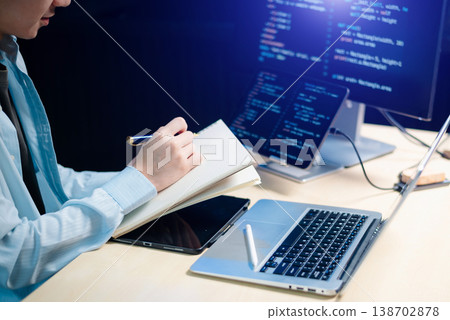 Male programmer using stylus to analyze code on tablet and monitor. Software development, coding, and tech workspace concept Male programmer using stylus to analyze code on tablet and monitor. Software development, coding, and tech workspace concept 138702878