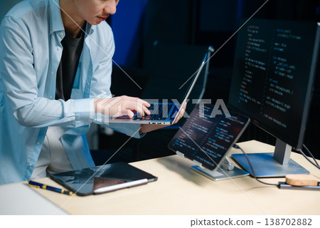 Asian male programmer working with tablet, laptop, and desktop in tech office. Coding, software development Asian male programmer working with tablet, laptop, and desktop in tech office. Coding, software development 138702882