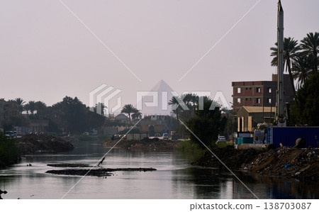 The Pyramid of Khafre, shrouded in mist across the city's waterfront, a landscape where modernity and antiquity intersect. 138703087
