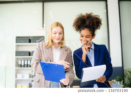 Dynamic teamwork in a modern office setting with diverse professionals brainstorming, collaborating, and achieving success. 138703190