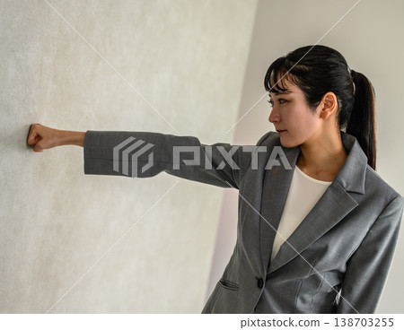 A woman with her fists raised, facing the wall. 138703255