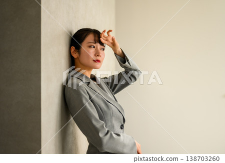 一位女商人倚牆而立，陷入沉思。 138703260