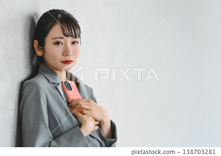 一位女商人手持智慧型手機，直視鏡頭。 138703281
