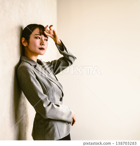 一位心事重重的女商人倚靠在牆上。 138703283