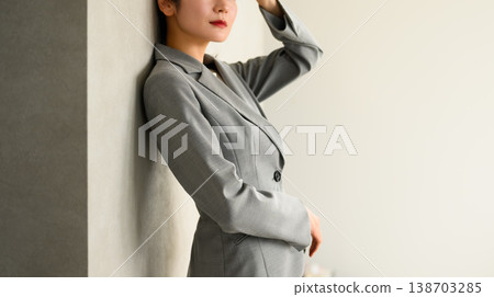 A businesswoman resting, leaning against a wall. 138703285