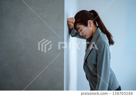 A tired businesswoman leaning against the wall A tired businesswoman leaning against the wall 138703288