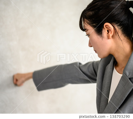 Businesswoman punching a wall Businesswoman punching a wall 138703290
