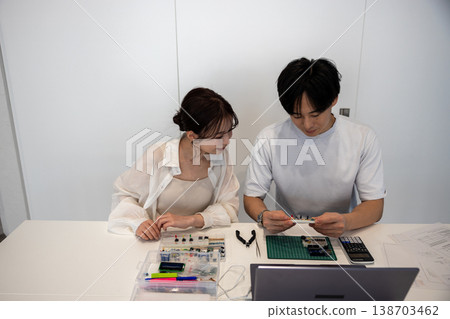 Young men and women studying electronic circuits 138703462