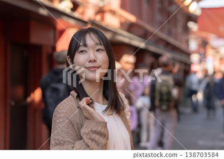 A young woman enjoying sightseeing in the old downtown area: Walking around Asakusa on a holiday. A young woman enjoying sightseeing in the old downtown area: Walking around Asakusa on a holiday. 138703584