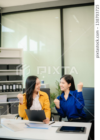 Business professionals collaborating in a modern office, planning and discussing ideas with laptops. 138703725