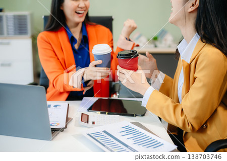 Business professionals collaborating in a modern office, planning and discussing ideas with laptops. 138703746