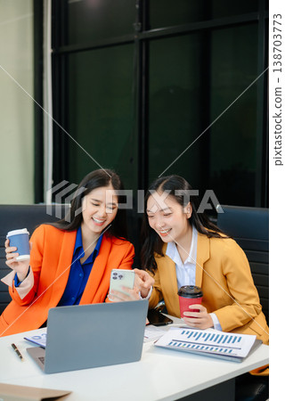 Business professionals collaborating in a modern office, planning and discussing ideas with laptops. 138703773