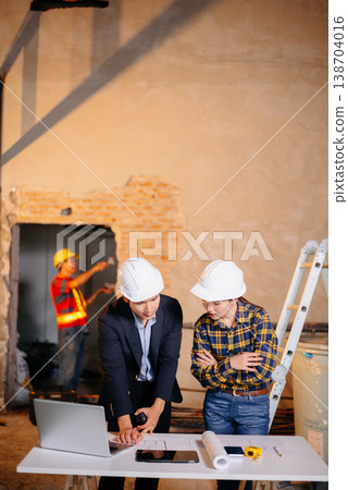 Two Asian colleagues discussing data working and tablet, laptop with architectural project at construction site 138704016