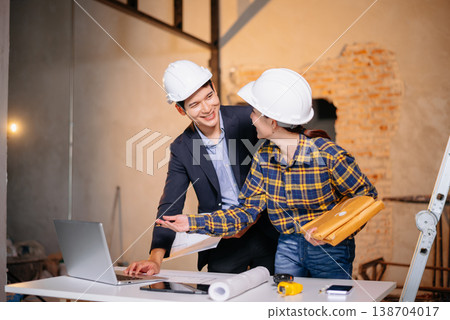 Asian construction professionals shaking hands in agreement at an indoor site. 138704017