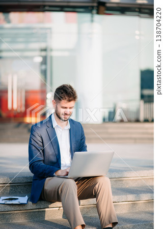 businessman works outdoors near the office holds a tablet, smiles reads good news 138704220