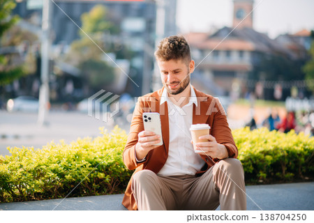businessman works outdoors near the office holds a tablet, smiles reads good news businessman works outdoors near the office holds a tablet, smiles reads good news 138704250