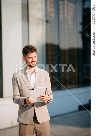 Businessman standing outdoors and using digital tablet. Perfect for corporate, technology, and professional themes Businessman standing outdoors and using digital tablet. Perfect for corporate, technology, and professional themes 138704269