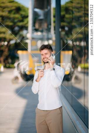 businessman works outdoors near the office holds a tablet, smiles reads good news businessman works outdoors near the office holds a tablet, smiles reads good news 138704312