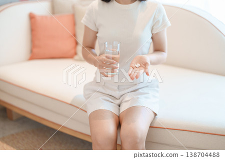 woman hand holding medicine painkiller pill and water glass on the sofa at home, taking for headaches, stomach ache, Diarrhea Pain from food poisoning, Endometriosis, Hysterectomy and Menstrual woman hand holding medicine painkiller pill and water glass on the sofa at home, taking for headaches, stomach ache, Diarrhea Pain from food poisoning, Endometriosis, Hysterectomy and Menstrual 138704488