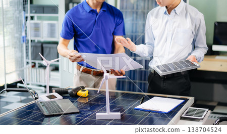 Two Asian engineers collaborate on solar and wind energy, driving clean innovation and sustainability. Two Asian engineers collaborate on solar and wind energy, driving clean innovation and sustainability. 138704524