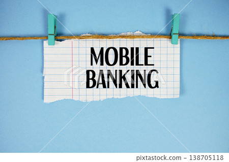Mobile Banking text written on rip paper with wooden clip on blue background Mobile Banking text written on rip paper with wooden clip on blue background 138705118