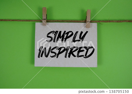 Simply Inspired text written on paper card with rope and wooden clip hanging 138705150
