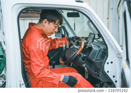 一名身穿工作服的男子駕駛著一輛輕型卡車。 138705292