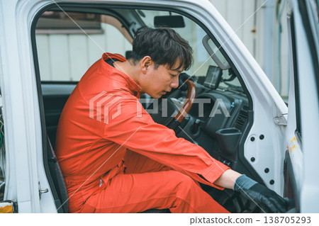 一名身穿工作服的男子駕駛著一輛輕型卡車。 一名身穿工作服的男子駕駛著一輛輕型卡車。 138705293