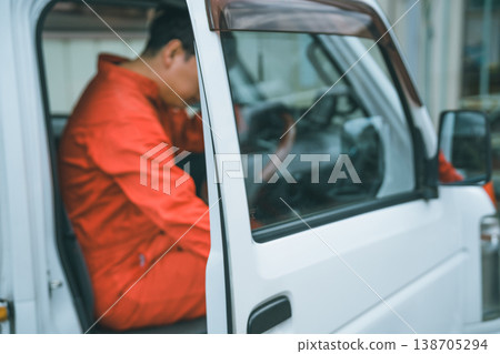 一名身穿工作服的男子駕駛著一輛輕型卡車。 一名身穿工作服的男子駕駛著一輛輕型卡車。 138705294