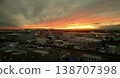 The setting sun shines through the gaps in the dramatic clouds. The city lights begin to twinkle, creating a nostalgic twilight atmosphere. 138707398