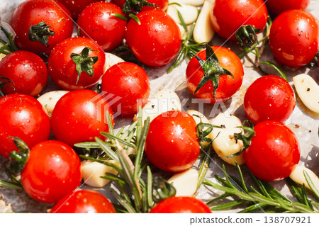 Fresh red cherry tomatoes with rosemary sprigs and garlic cloves on baking paper. Fresh red cherry tomatoes with rosemary sprigs and garlic cloves on baking paper. 138707921