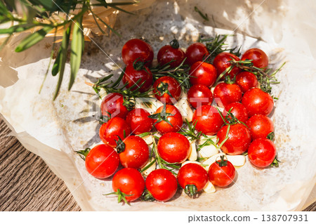 Fresh red cherry tomatoes with rosemary sprigs and garlic cloves on baking paper. Fresh red cherry tomatoes with rosemary sprigs and garlic cloves on baking paper. 138707931