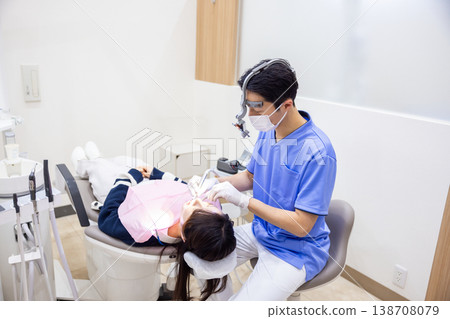 A male dentist performing treatment while wearing dental loupes. A male dentist performing treatment while wearing dental loupes. 138708079