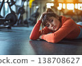 Young woman resting on a gym floor after an intense workout session 138708627