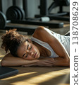 Young woman resting on a gym floor after an intense workout session 138708629